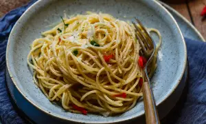 Spaghetti Aglio e Olio mit Chili und Parmesan in einer Schüssel, daneben eine Gabel.