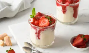 Zwei Gläser mit Erdbeer-Dessert, garniert mit Minze und Erdbeerscheiben.