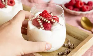 Cremiges Mascarpone-Dessert mit Himbeeren und Schokoröllchen im Glas.