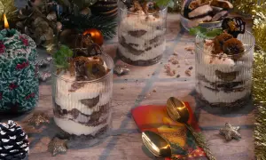 Festliche Desserts im Glas mit Bananen und Sahne, dekoriert mit Minze und Schokolade.