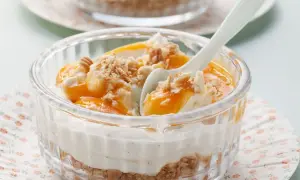 Schichtdessert mit Mascarpone, Fruchtpüree und Keksbröseln in einem Glas.