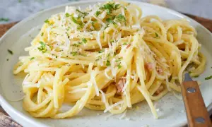 Spaghetti Carbonara mit geriebenem Parmesan und Petersilie auf einem Teller.