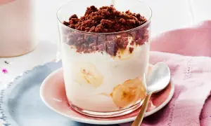 Dessert im Glas mit Bananenscheiben, Sahne und Schokostreuseln.