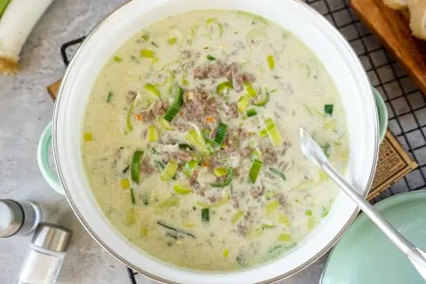 Cremige Lauchsuppe mit Hackfleisch in einem Topf, garniert mit Lauchringen.