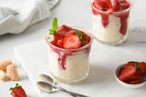 Zwei Gläser mit Erdbeer-Dessert, garniert mit Minze und Erdbeerscheiben.