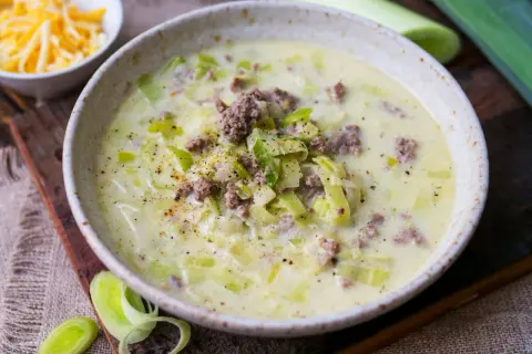 Cremige Lauchsuppe mit Hackfleisch und Käse, garniert mit Pfeffer.