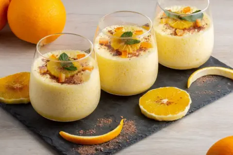 Orangendessert im Glas mit Orangenscheiben und Schokostreuseln.