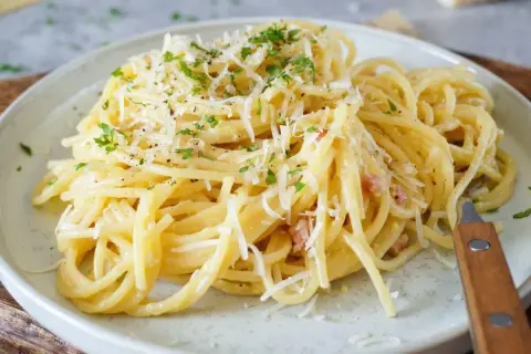 Spaghetti Carbonara mit geriebenem Parmesan und Petersilie auf einem Teller.