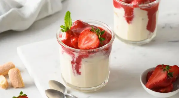 Zwei Gläser mit Erdbeer-Dessert, garniert mit Minze und Erdbeerscheiben.