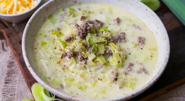 Cremige Lauchsuppe mit Hackfleisch und Käse, garniert mit Pfeffer.