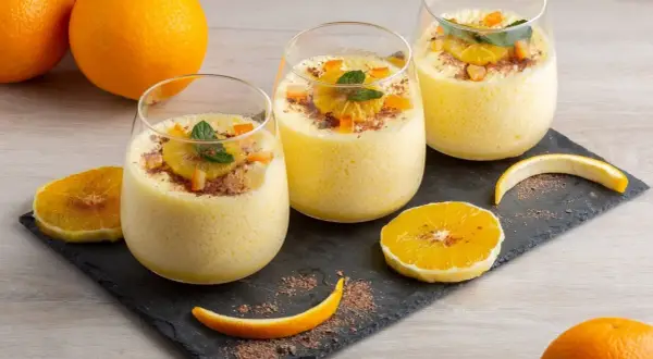 Orangendessert im Glas mit Orangenscheiben und Schokostreuseln.
