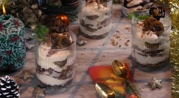 Festliche Desserts im Glas mit Bananen und Sahne, dekoriert mit Minze und Schokolade.