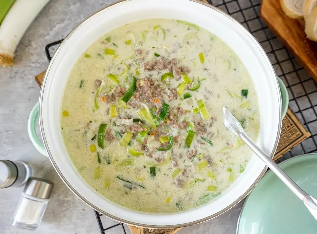 Cremige Lauchsuppe mit Hackfleisch in einem Topf, garniert mit Lauchringen.