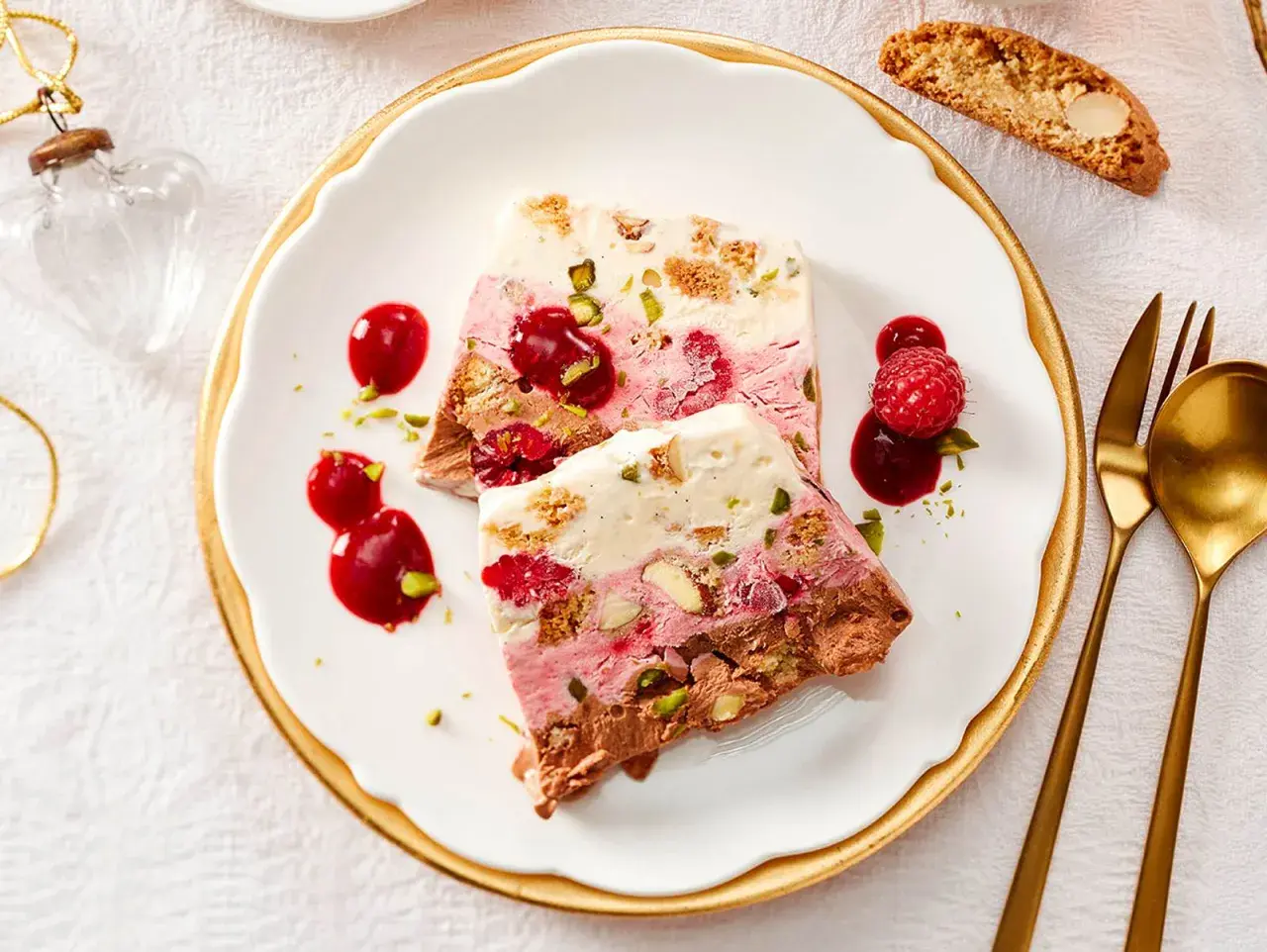 Gefrorenes Dessert mit Schichten aus Schokolade, Beeren und Nüssen, garniert mit Beeren und Sauce.