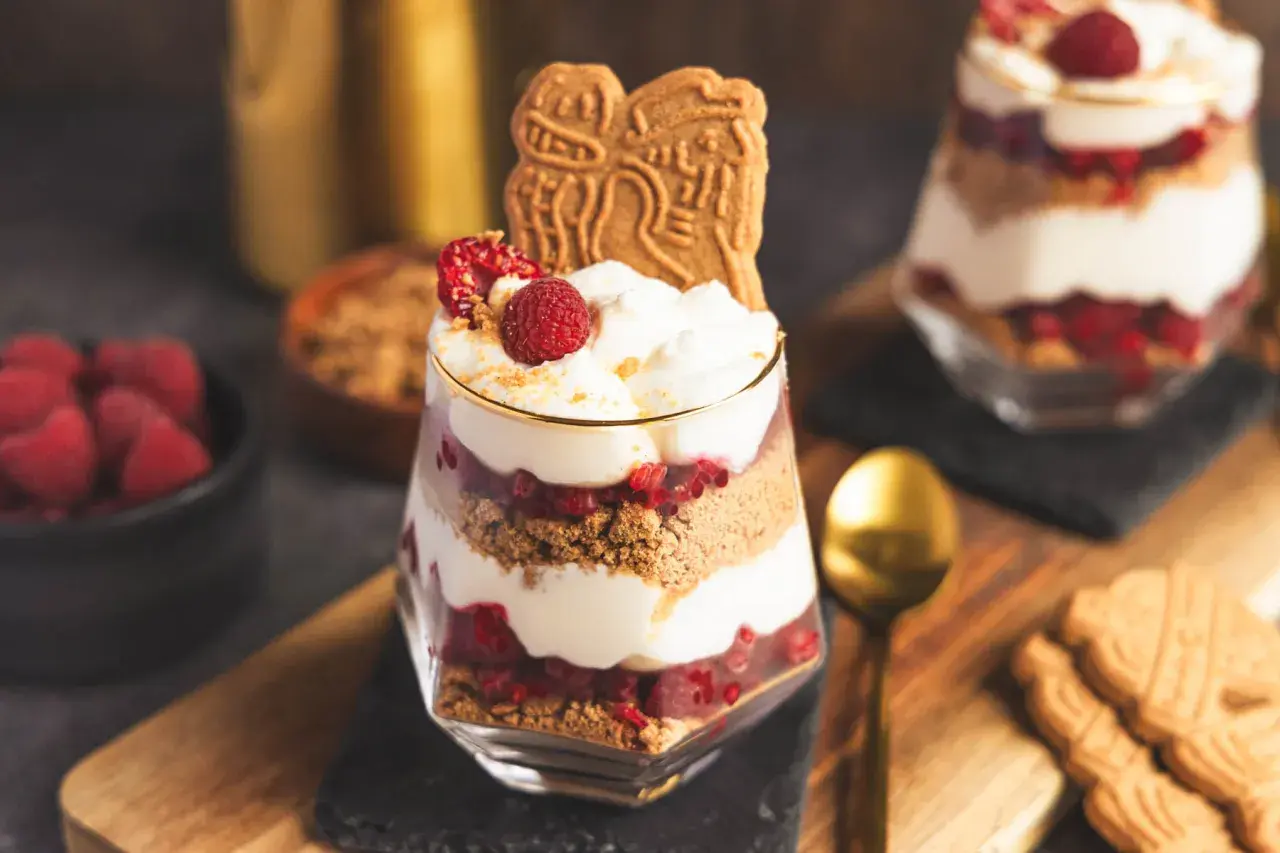 Spekulatius-Himbeer-Dessert im Glas mit Sahne und frischen Himbeeren, garniert mit Spekulatius.