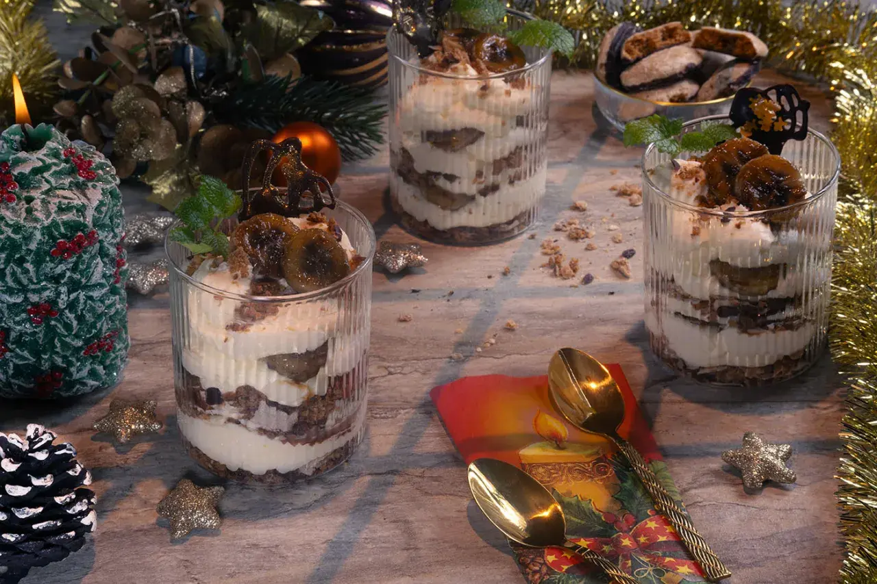 Festliche Desserts im Glas mit Bananen und Sahne, dekoriert mit Minze und Schokolade.
