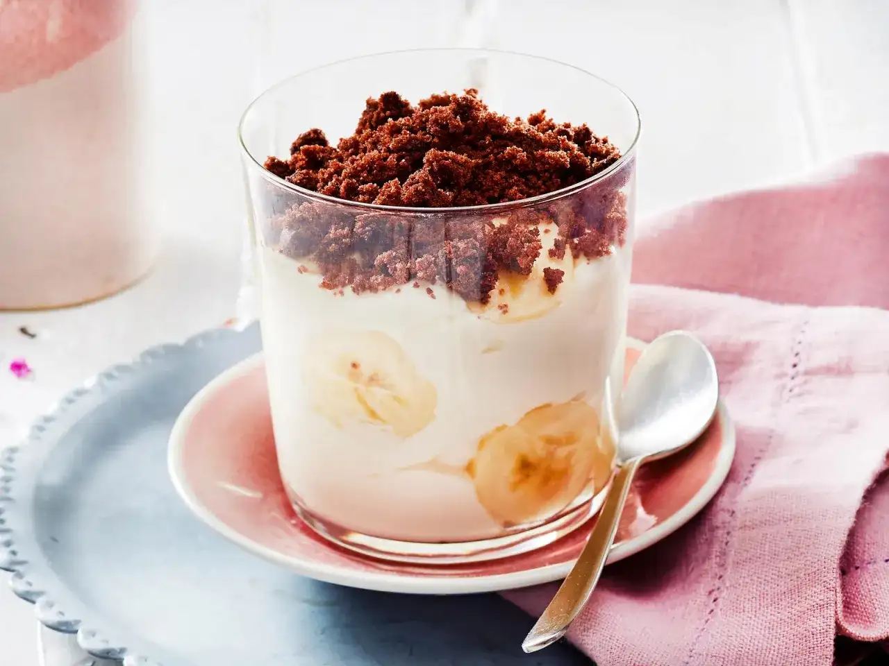 Dessert im Glas mit Bananenscheiben, Sahne und Schokostreuseln.