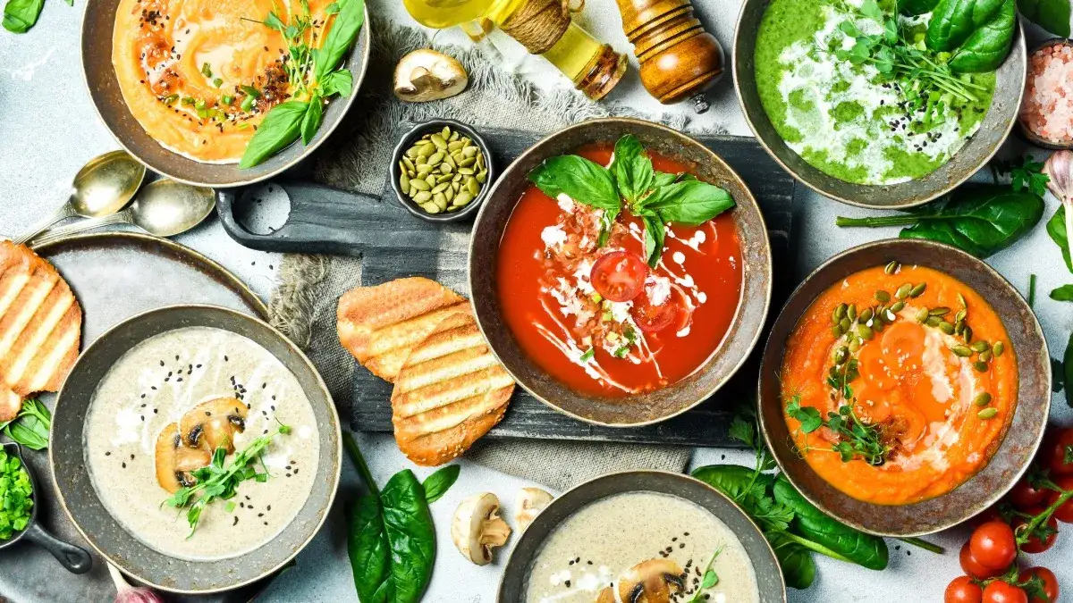 verschiedene Suppen-Toppings in kleinen Schalen wie Croutons, Kr&auml;uter, Kerne und Chili-&Ouml;l