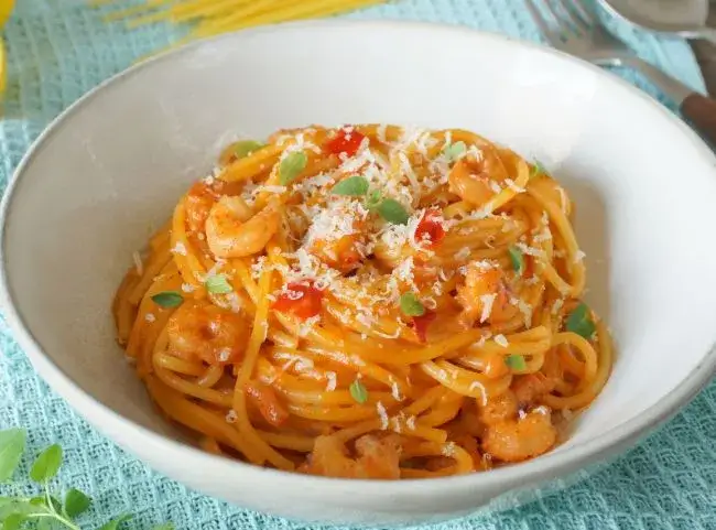 Nudeln mit Garnelen in Tomaten-Sahne-So&szlig;e auf einem Teller