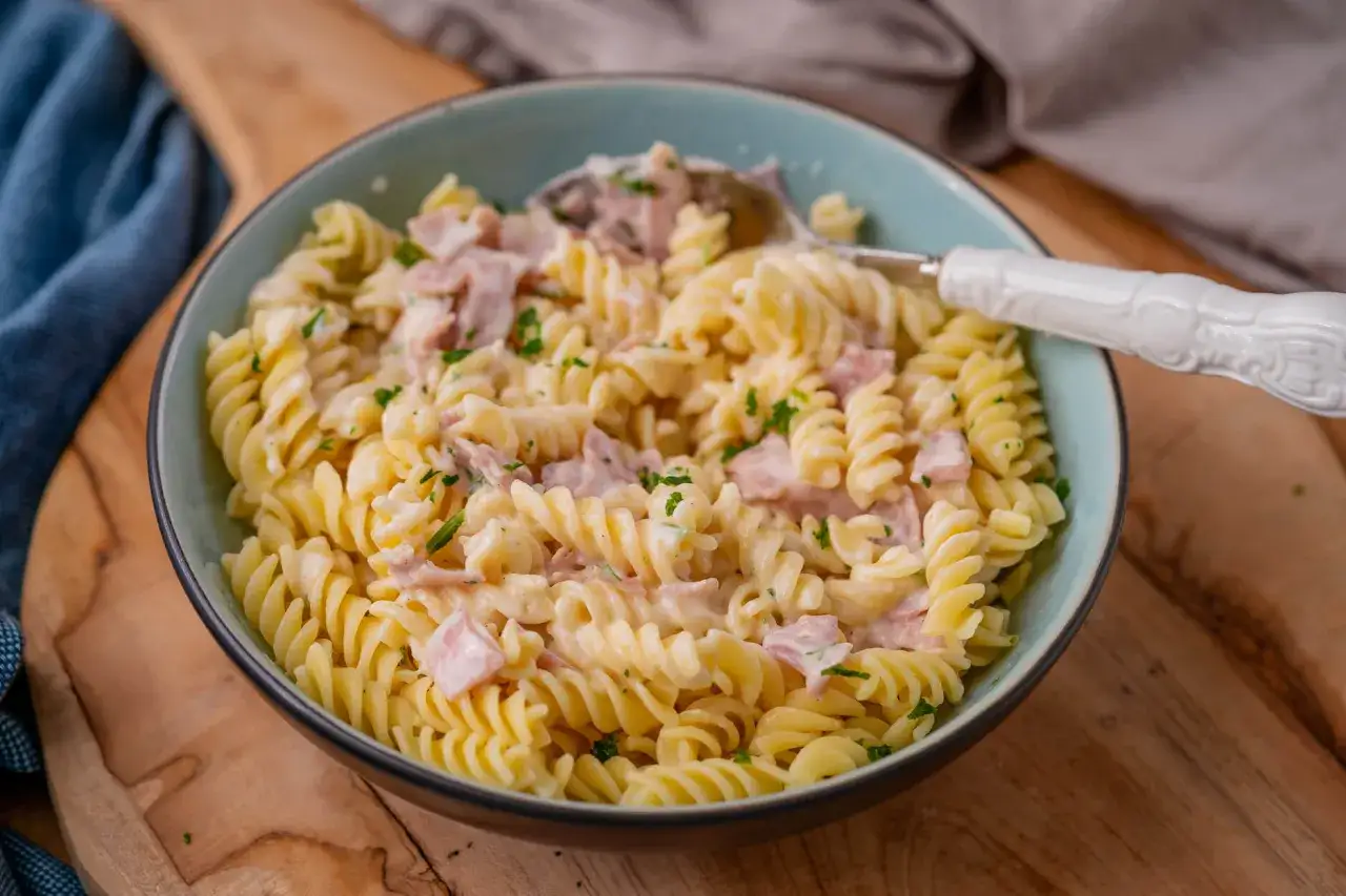 Zutaten f&uuml;r Nudeln mit Sahnesauce auf einem Holztisch Sahne Zwiebel Knoblauch Parmesan