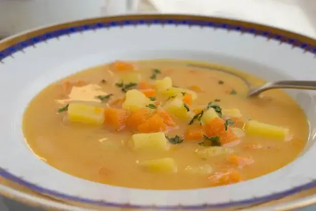 Zutaten für Kartoffel Karotten Suppe auf einem Holztisch