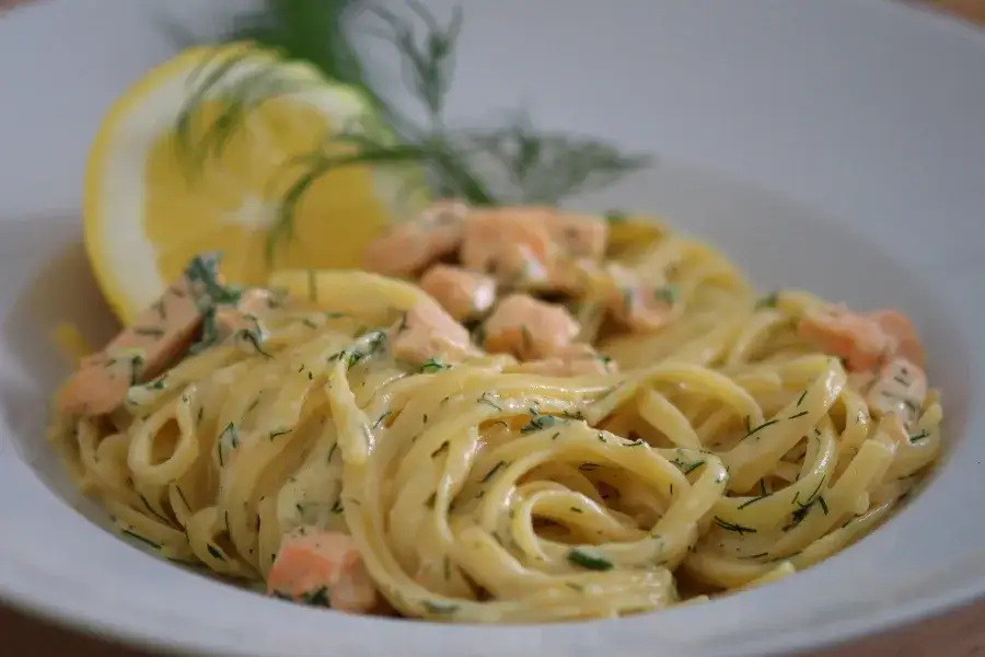 Pasta mit Lachs-Sahnesauce und Zitrone auf einem Teller