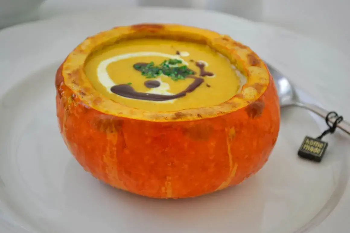 Zutaten f&uuml;r K&uuml;rbis-Curry-Suppe auf einem Holztisch angerichtet