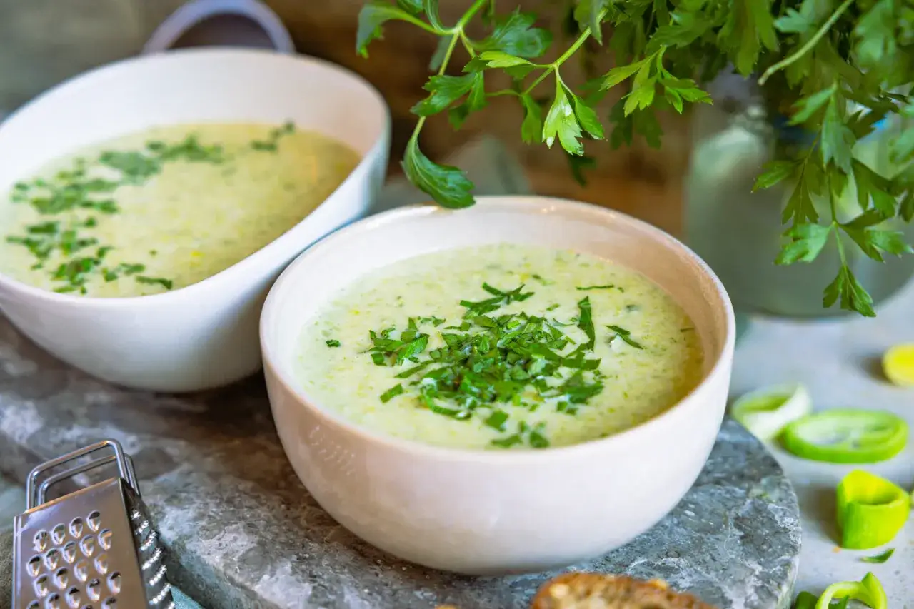 cremige Porreesuppe in einer Sch&uuml;ssel mit frischen Kr&auml;utern und Croutons