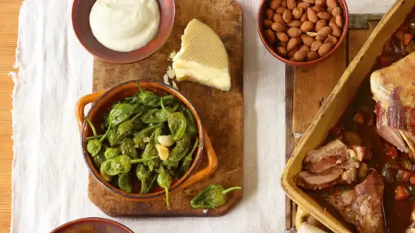 Tapas-Gerichte: Gebratene grüne Paprika, Käse, Mandeln und ein Braten.