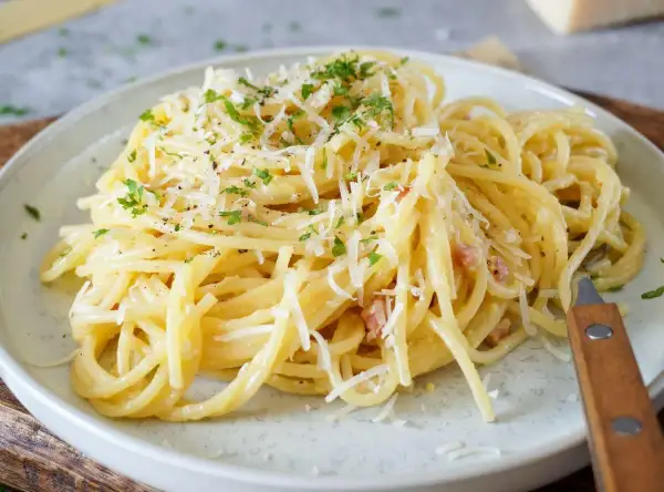 Spaghetti Carbonara mit geriebenem Parmesan und Petersilie auf einem Teller.